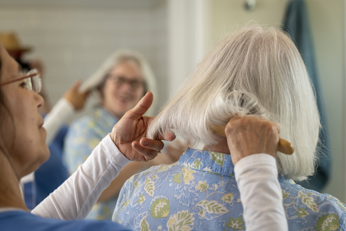 ComForCare Caregiver helping a senior woman to brush her hair