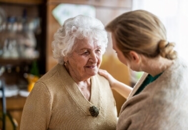 Younger woman talking to a senior woman in a comforting way with her hand on shoulder in Waukesha County.
