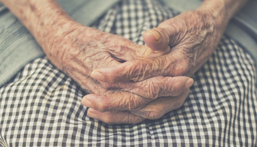Hands of an older person folded in their lap.
