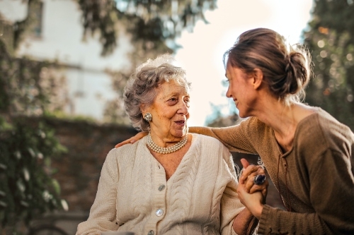 A younger woman putting her arm around an older lady.