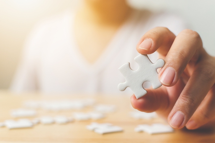 A hand holding up a puzzle piece.
