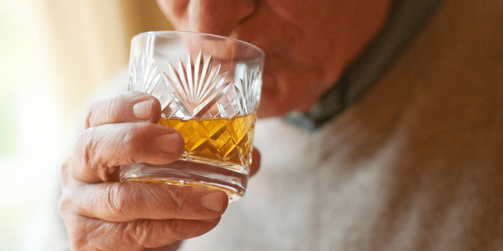 An older gentleman sipping whiskey.
