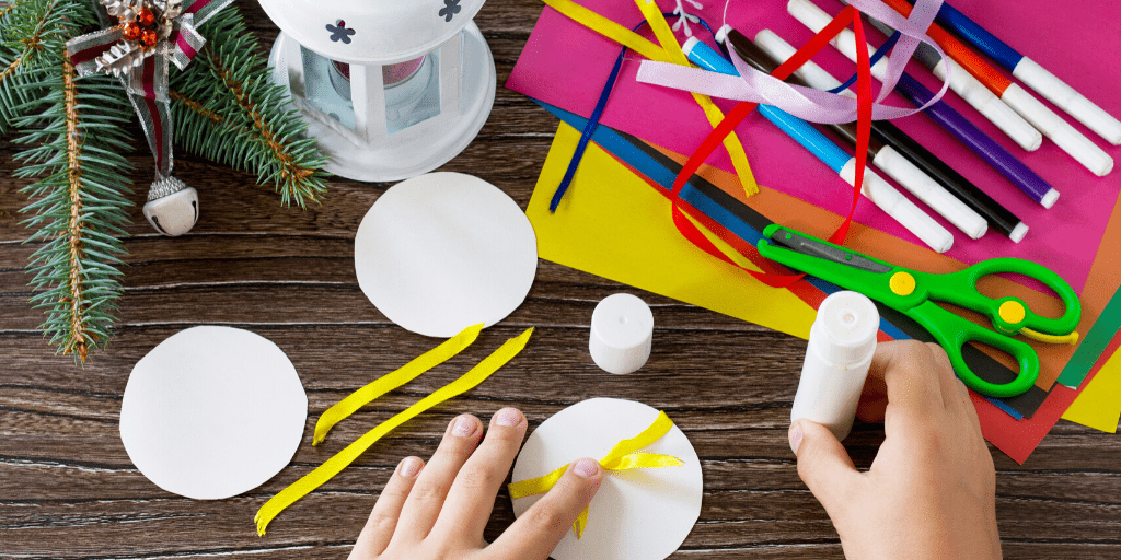 Hands working with crafting supplies to create Christmas crafts.
