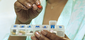 An older person working with a weekly medication dispenser.