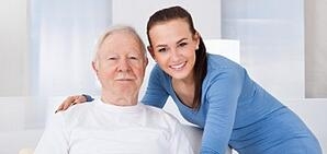 A caregiver posing for a photo with an older gentleman.