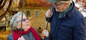 An older couple sitting on a swing during a Fall day.