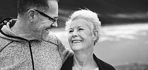 A black and white photo of an older couple walking outdoors.