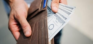 An older person showing the cash in their wallet.