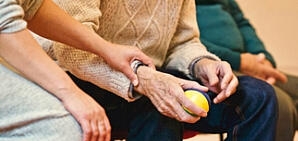 A person laying a hand on an older person in a comforting way.