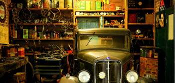 A photo of a historic car in a garage workshop area.