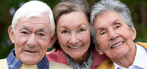 A photo of an older couple with their daughter in the middle hugging them.