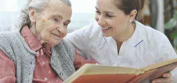 A caregiver reviewing a photo album with an older lady.