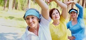 3 older woman doing yoga poses in the park.