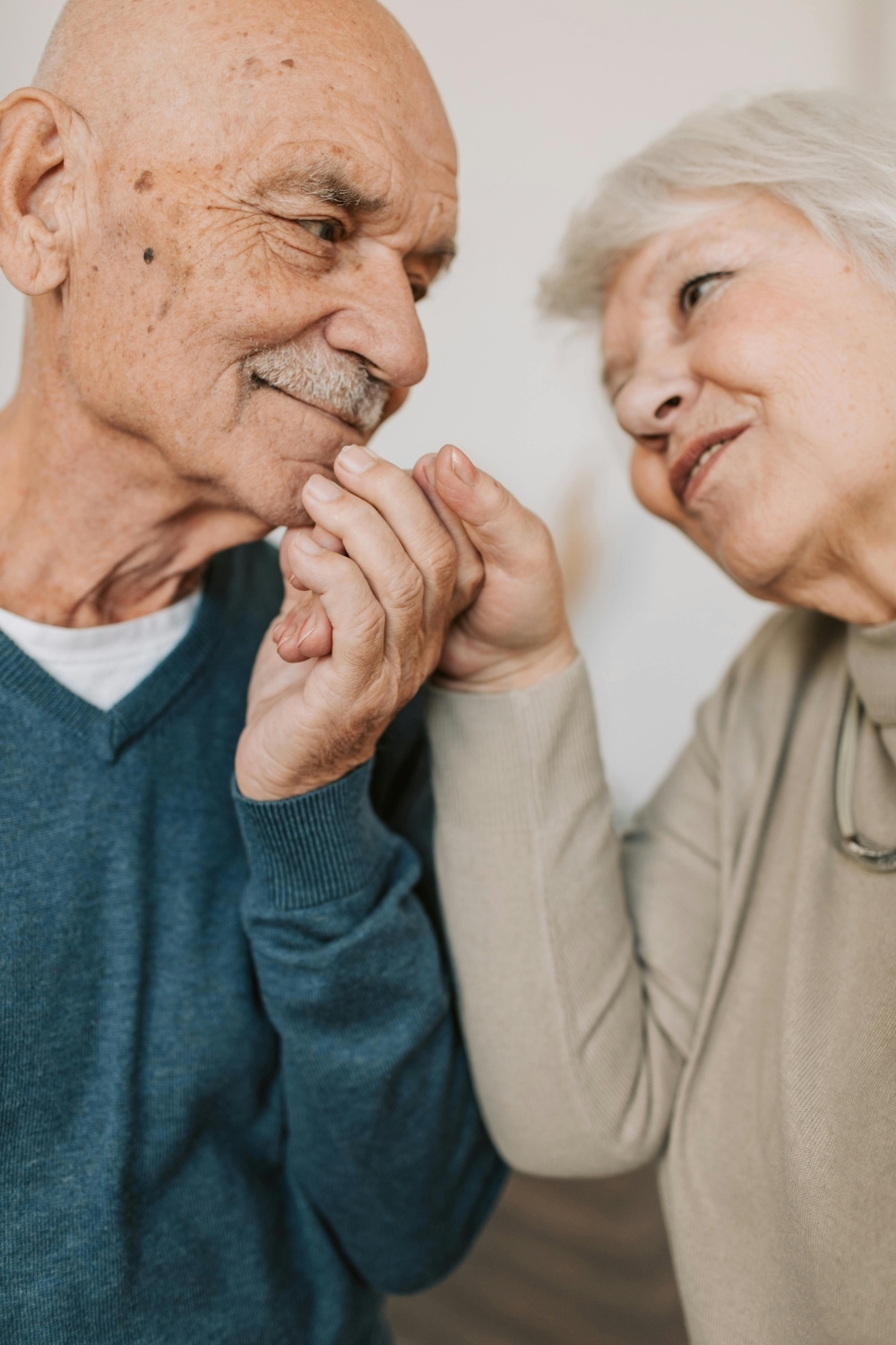 An older couple holding hands and looking lovingly into each other's eyes.