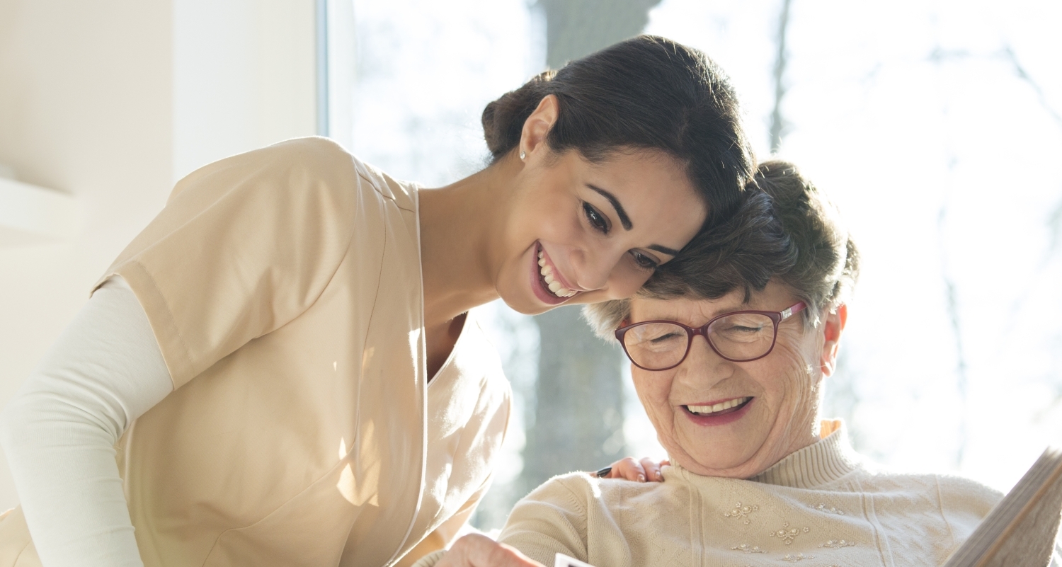 A caregiver looking through a photo album with an older lady.