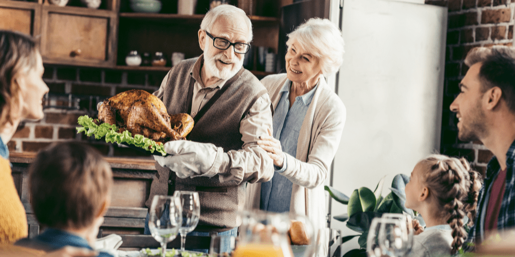 An older couple serving the Thanksgiving turkey to their family.